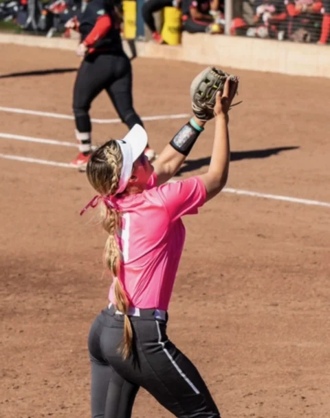 Fielder reaching up with her glove to make a catch